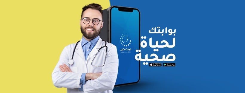Male doctor in white coat and glasses standing next to smartphone with Arabic health app interface on blue and yellow background
